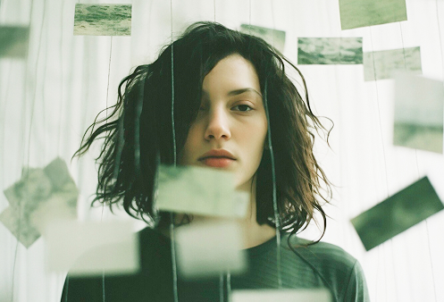 Uma mulher caminhando em um ambiente caótico com vários papéis voando ao seu redor, ilustrando a confusão e a busca por autoconhecimento em meio à desordem da vida.