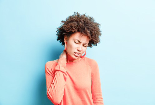 Uma mulher com a mão no pescoço, expressando desconforto e dor em seu rosto, simbolizando o desafio contínuo de lidar com uma condição de saúde ou dor crônica.